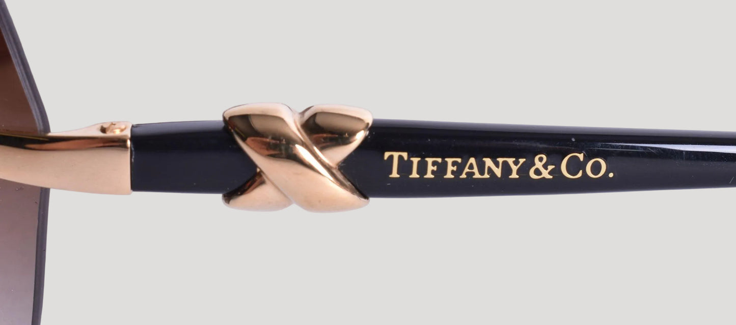 Tiffany & Co. sunglasses with gold and black design on a light gray background