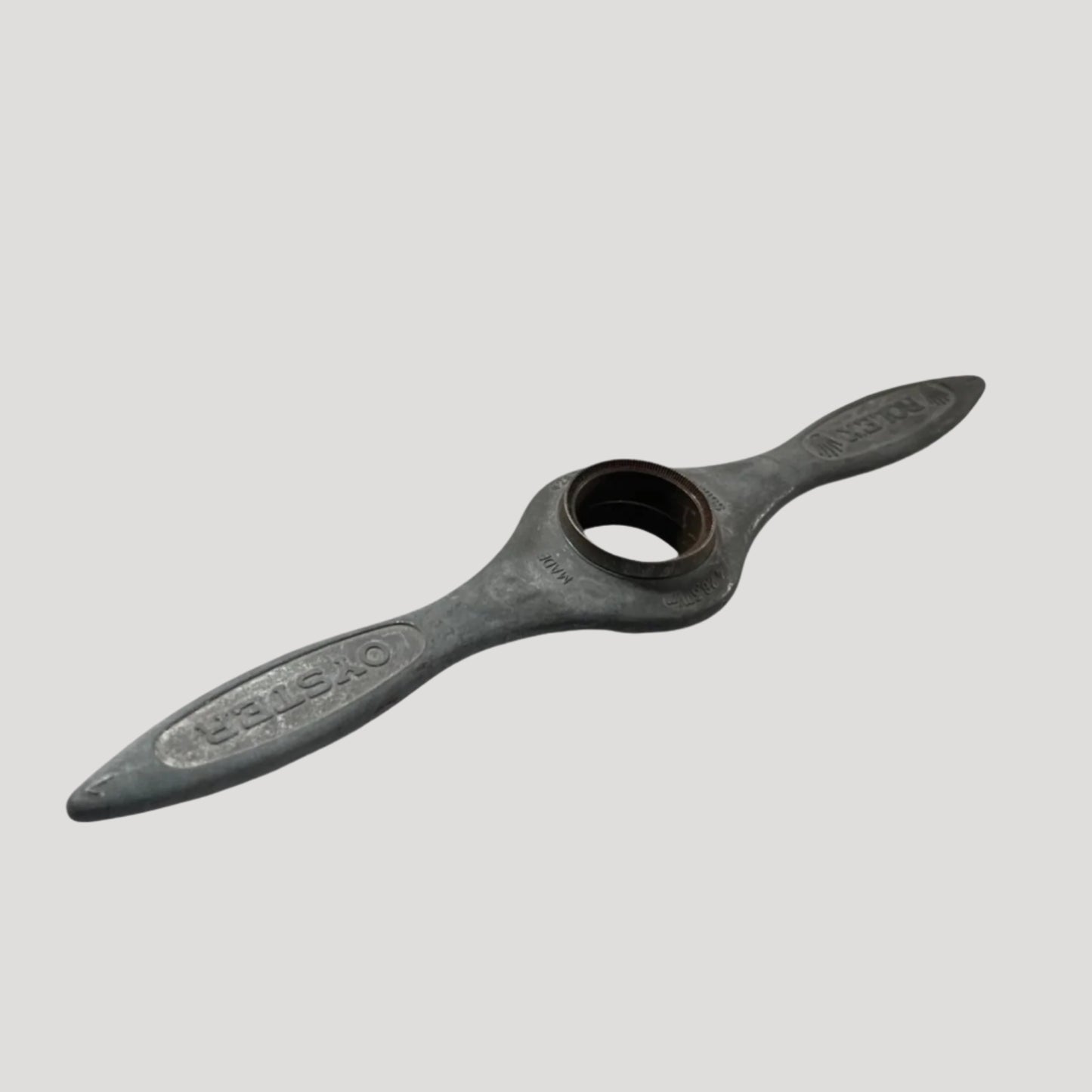 A black cast iron watch case opener with the Rolex logo embossed on the handle.