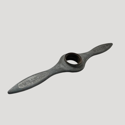 A black cast iron watch case opener with the Rolex logo embossed on the handle.
