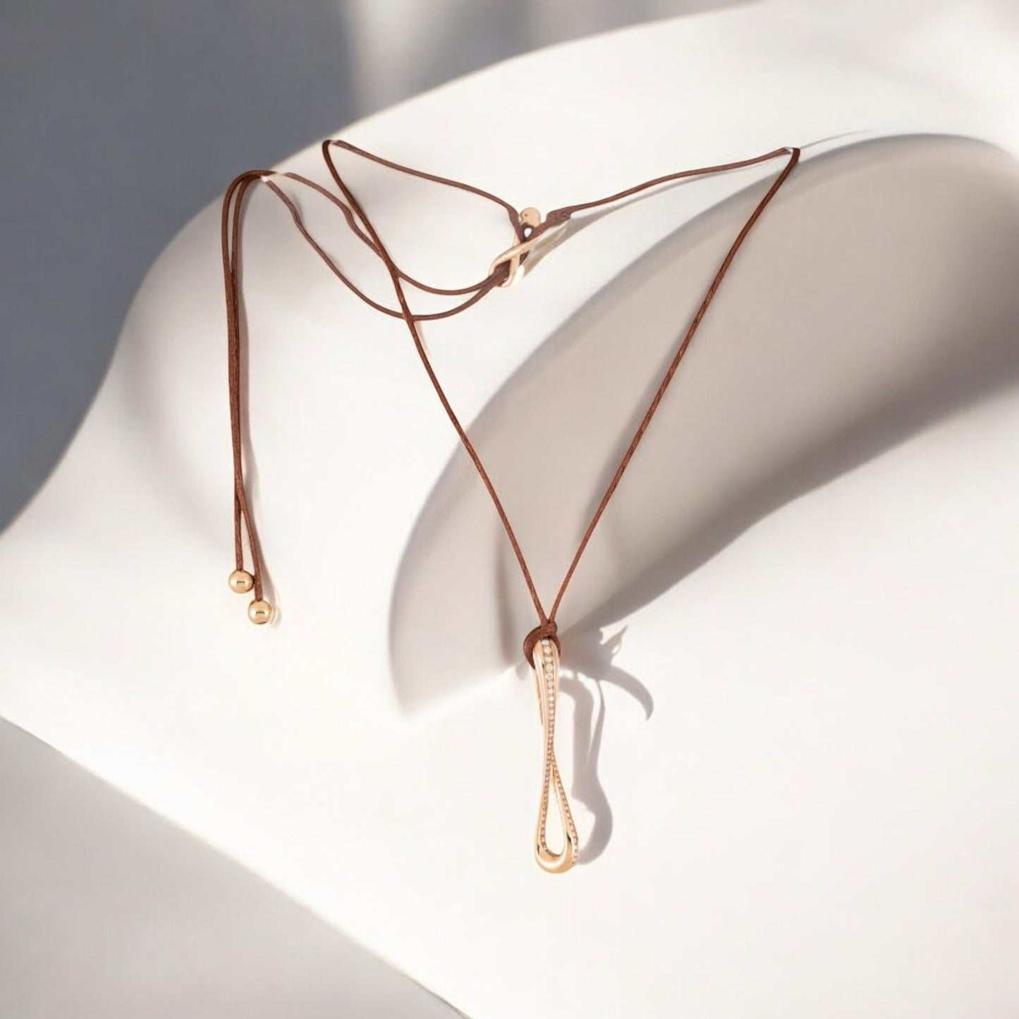 Infinity pendant in 18k rose gold set with brilliant-cut diamonds on brown satin lace